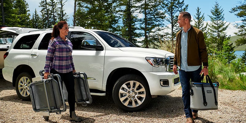 A man and woman unload camping supplies from a 2022 Toyota Sequoia