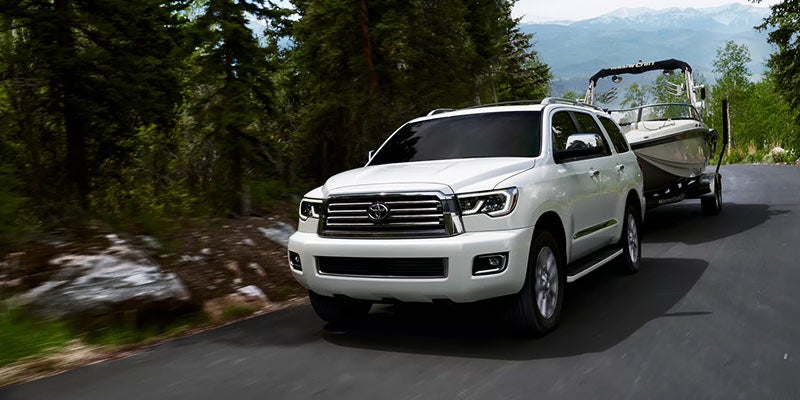 A white 2022 Toyota Sequoia tows a boat